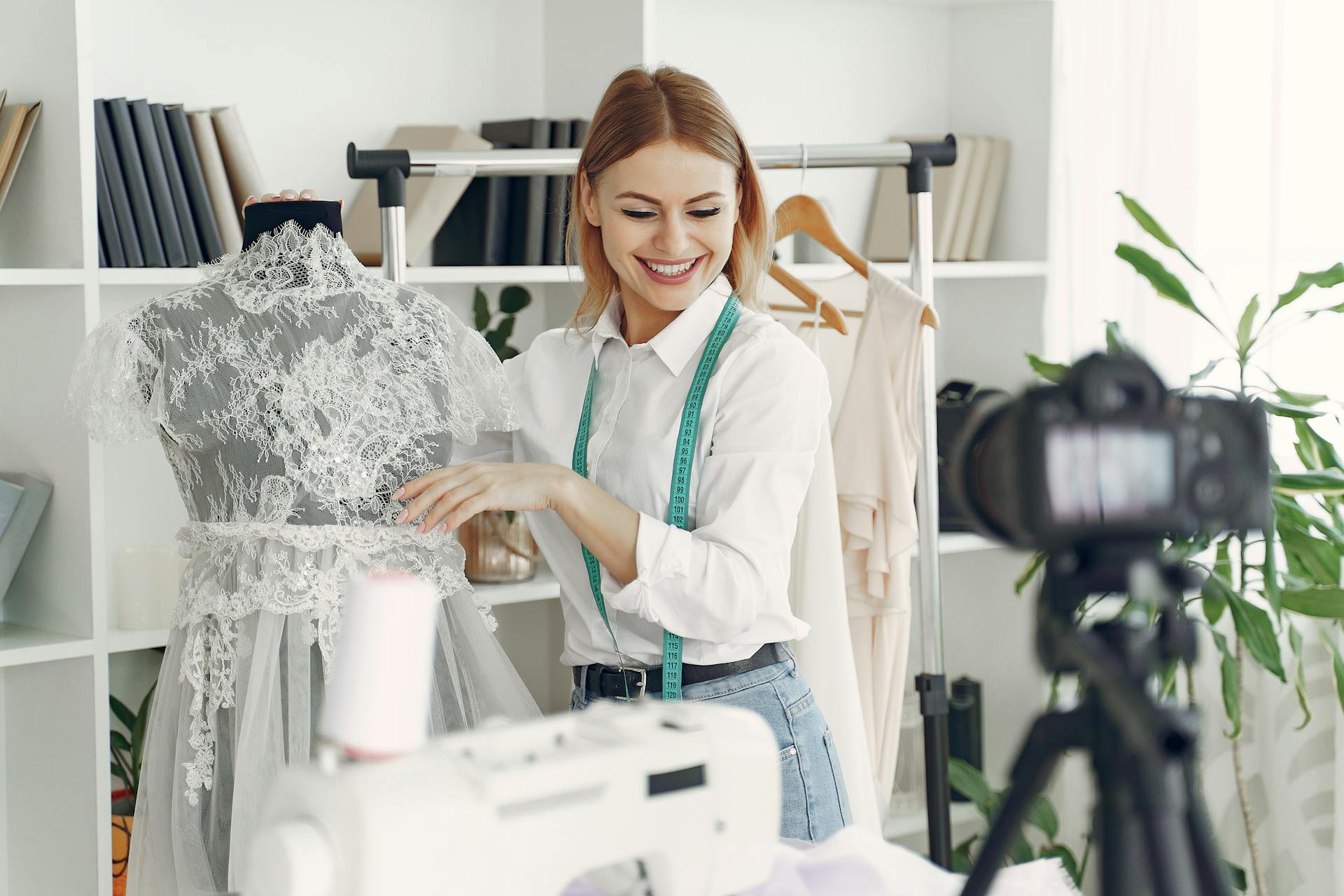 A happy dressmaker standing next to a bridal gown in her shop | Source: Pexels