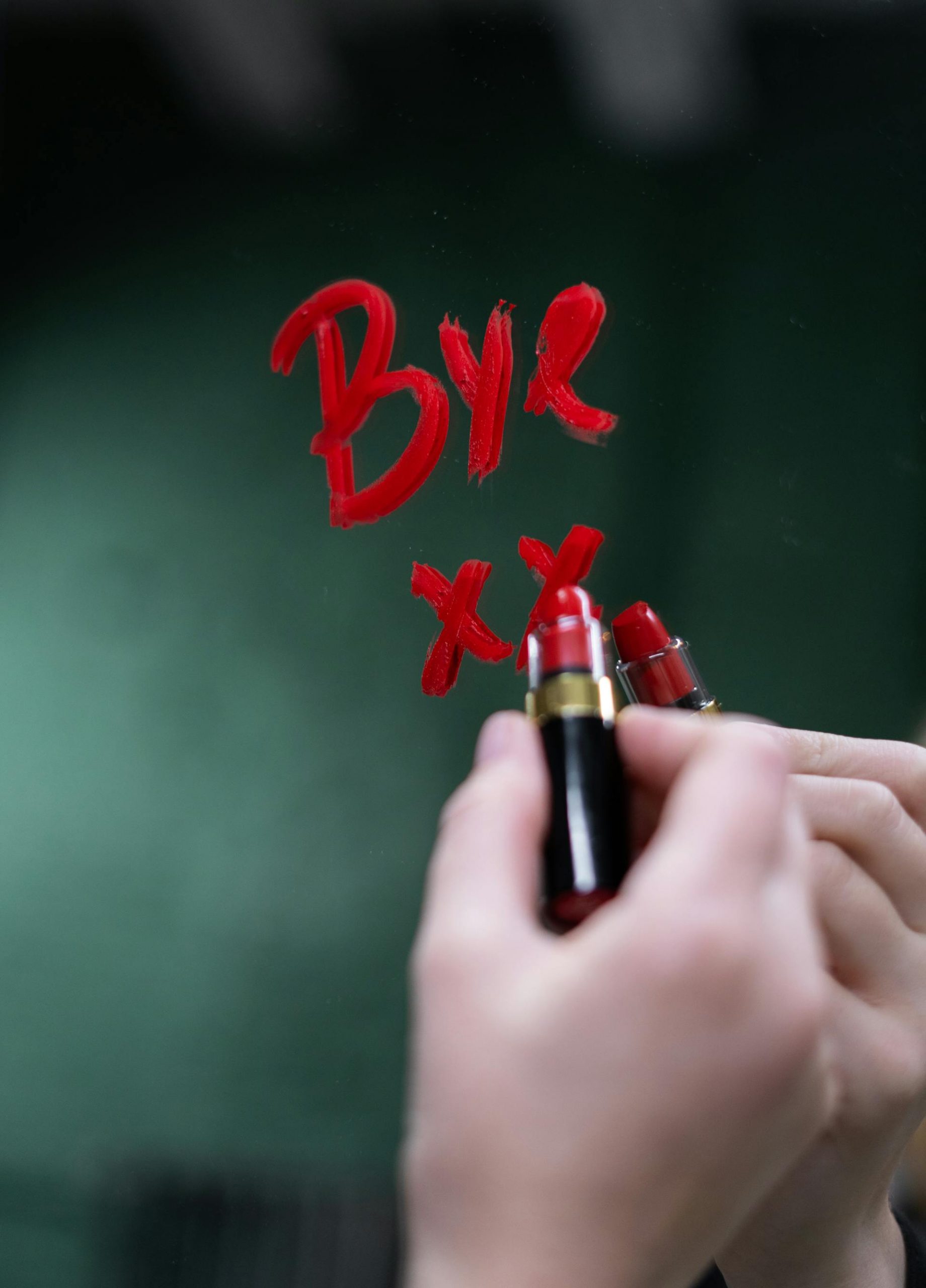 Close-up shot of a woman writing with red lipstick on a mirror | Source: Pexels