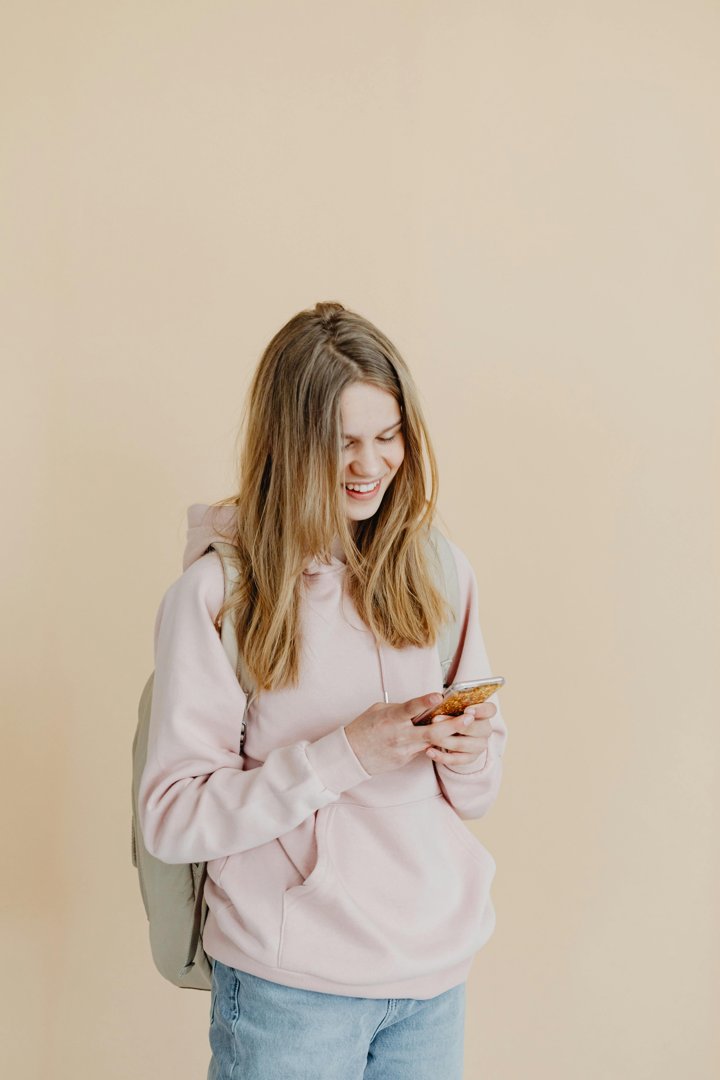 A happy girl looking at her phone | Source: Pexels
