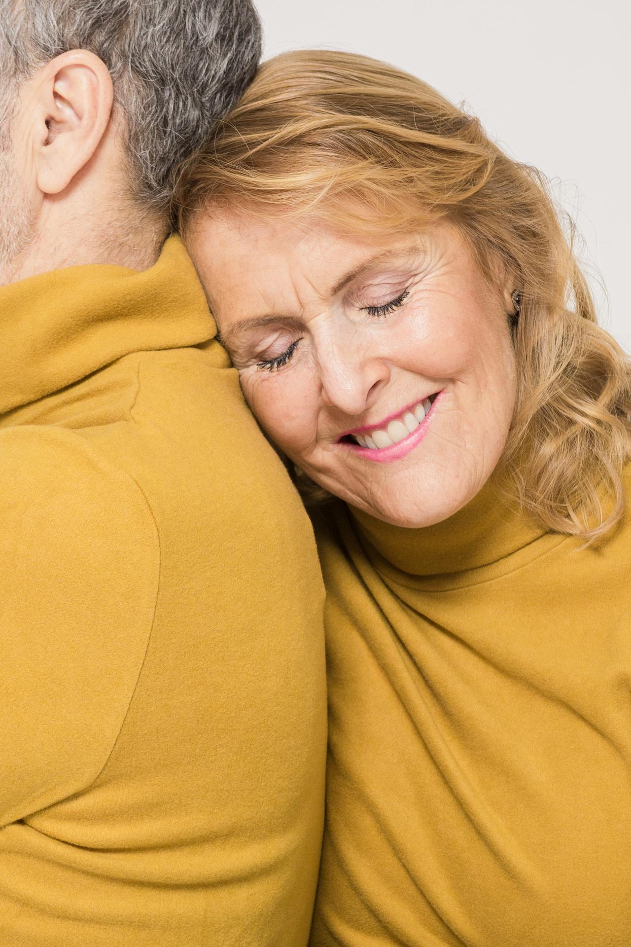 A relieved and delighted older woman leaning on a man's shoulder | Source: Pexels