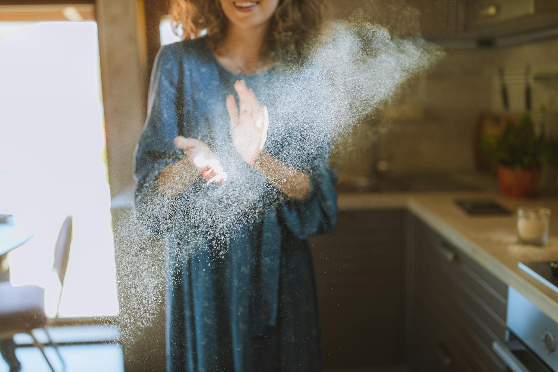 A woman clapping her flour-dusted hands | Source: Pexels