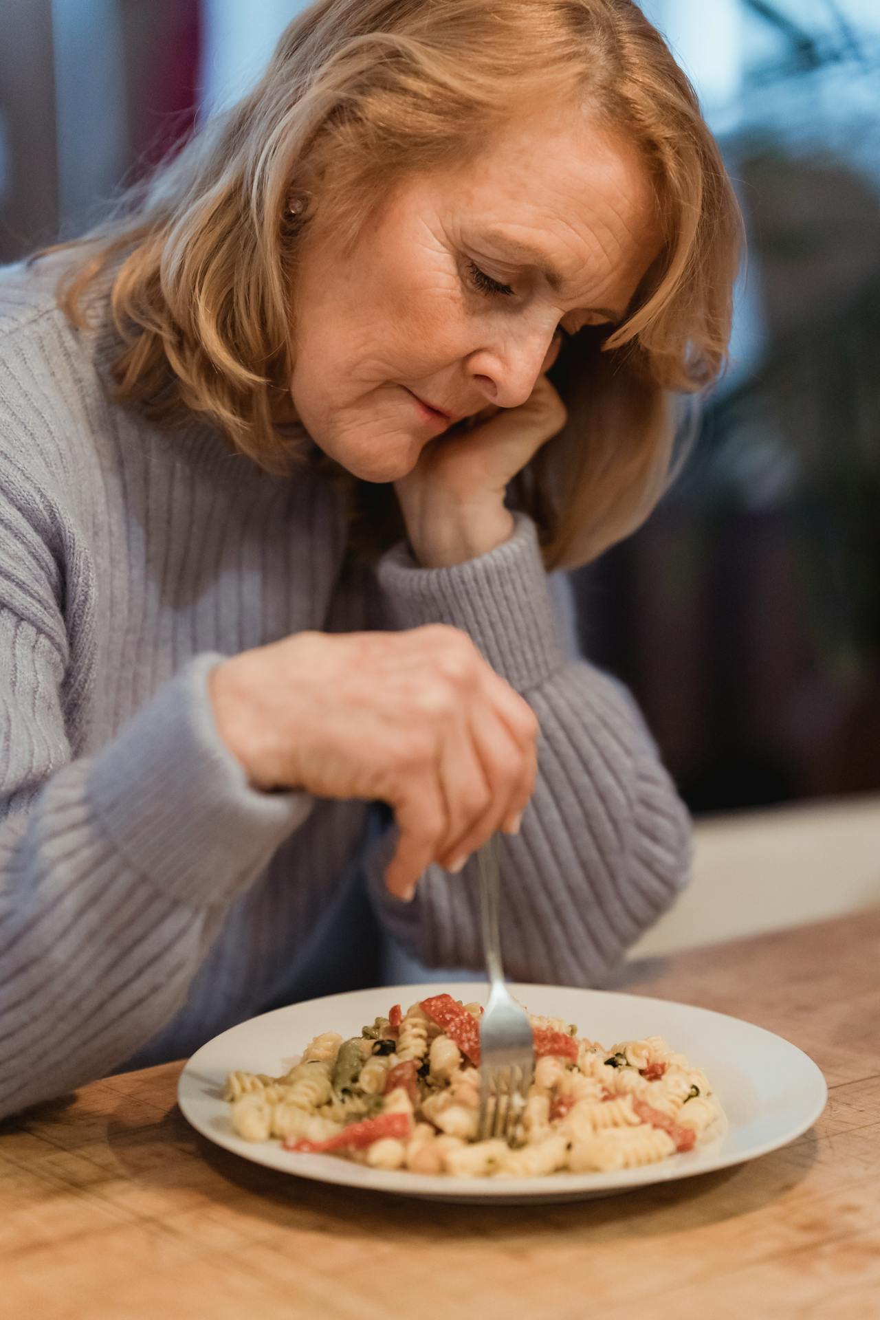 A sad woman staring at her plate of pasta | Source: Pexels