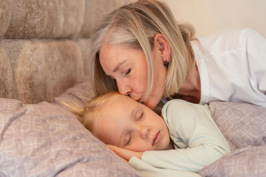 A grandmother tucking her granddaughter in bed | Source: Pexels
