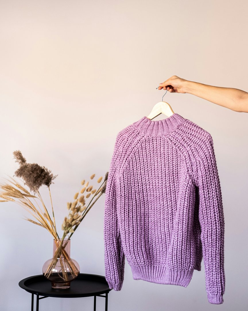 A woman holding up a sweater | Source: Unsplash