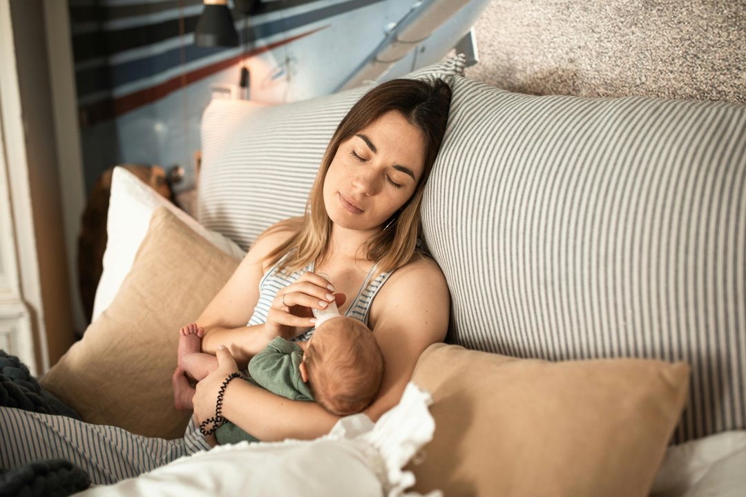 An exhausted woman feeding a baby | Source: Pexels