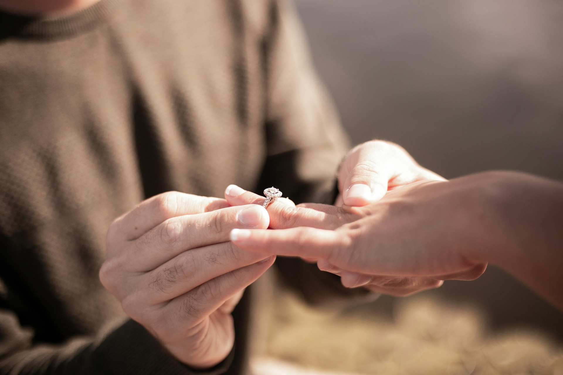 Close-up cropped shot of a man slipping a ring onto a woman's finger | Source: Unsplash