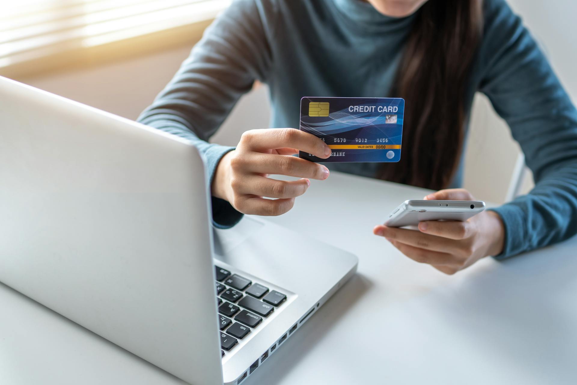 A woman holding her credit card and phone | Source: Pexels