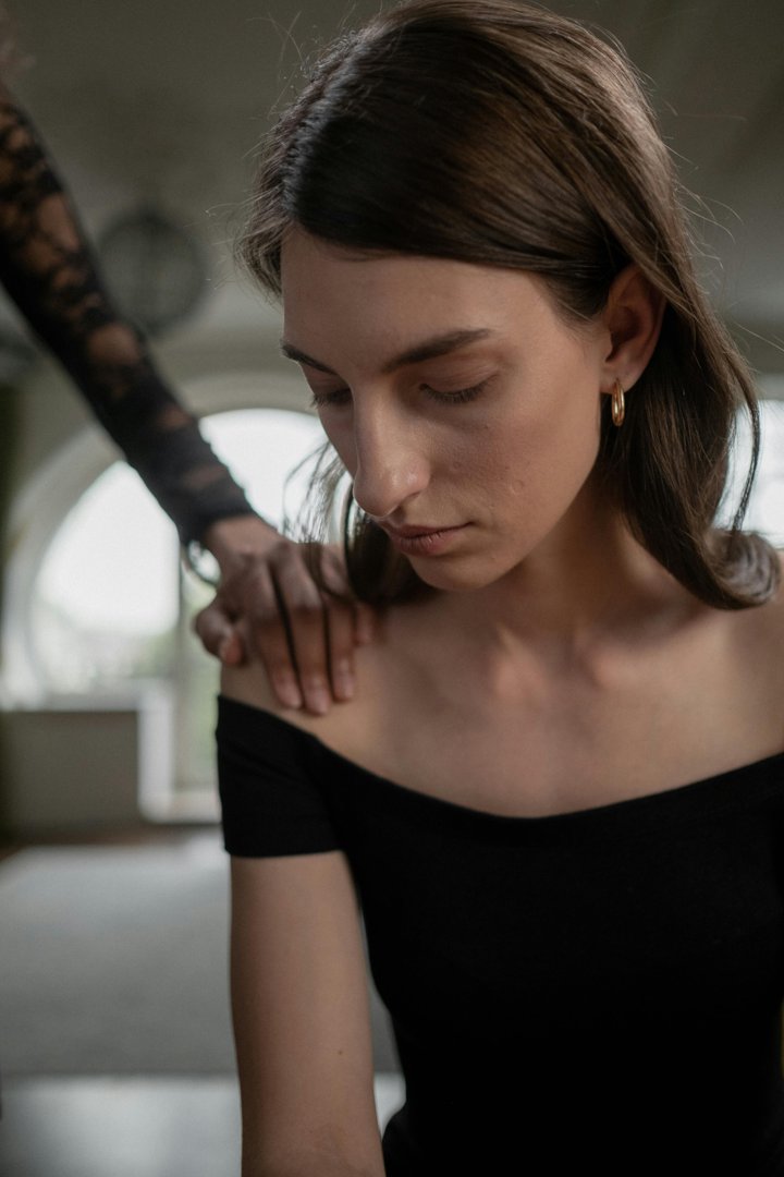 A sad woman facing down while being comforted | Source: Pexels