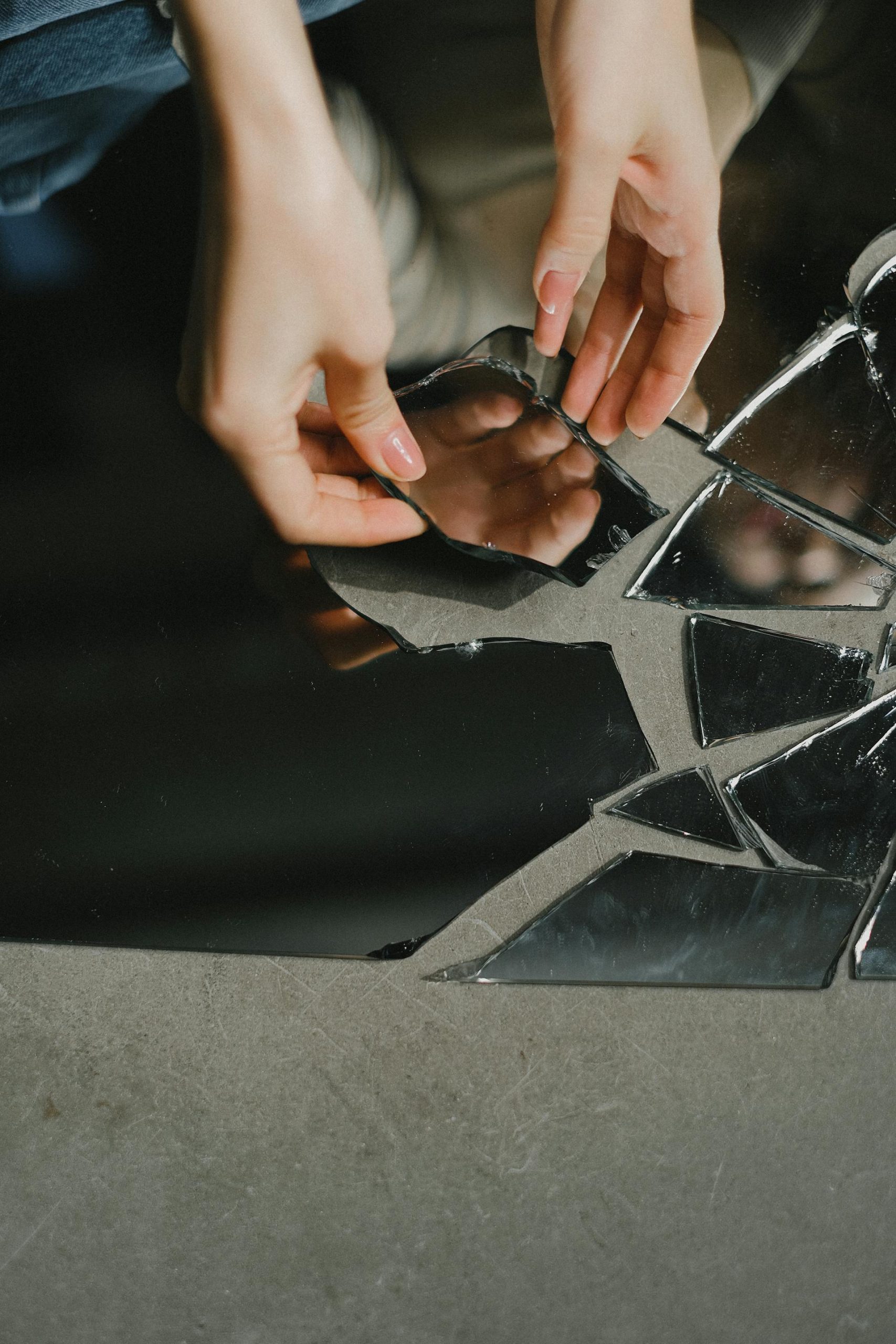 A woman touching a broken piece of mirror | Source: Pexels