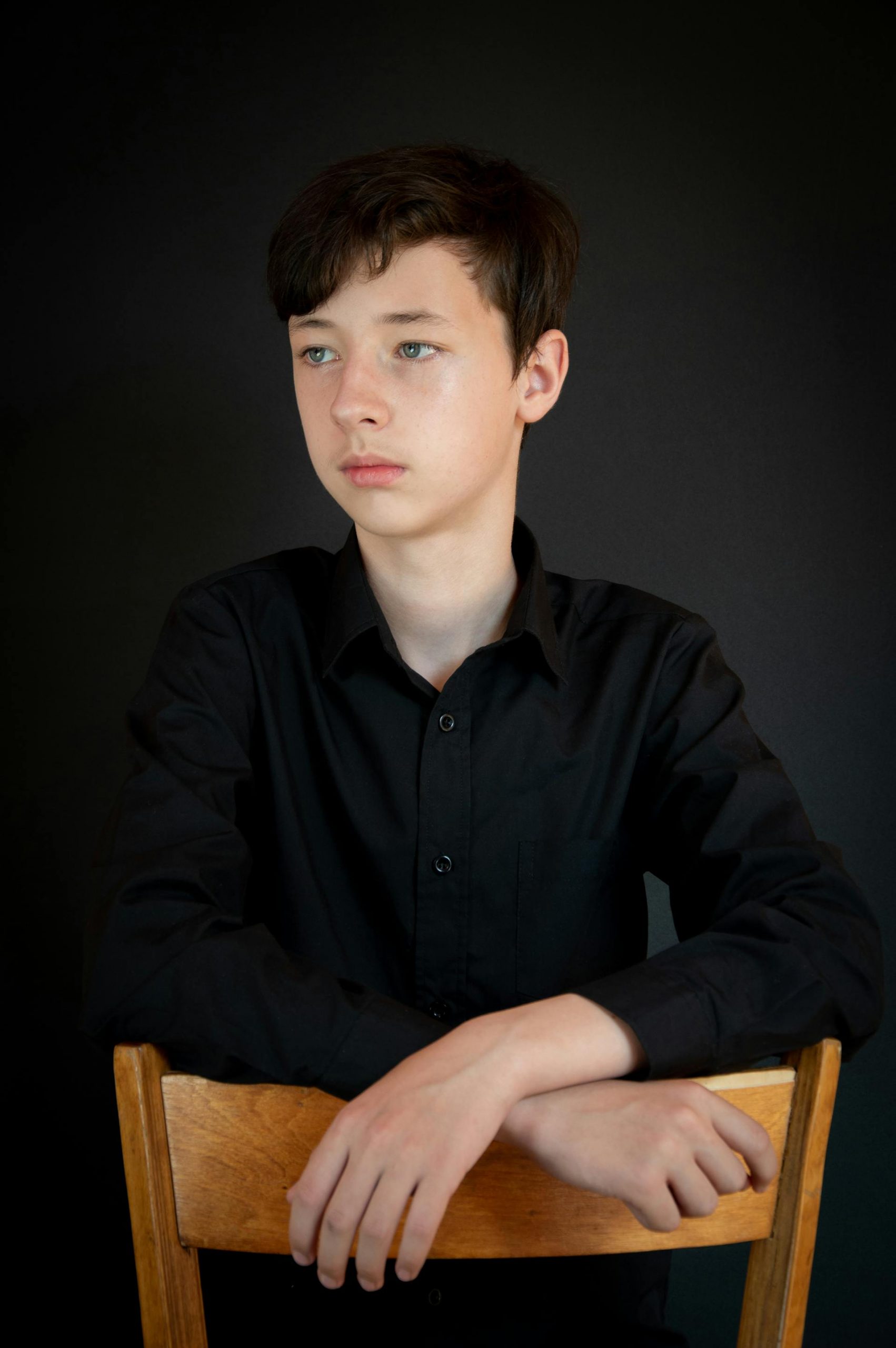 A teenage boy looking at someone with his hands resting on a chair | Source: Pexels