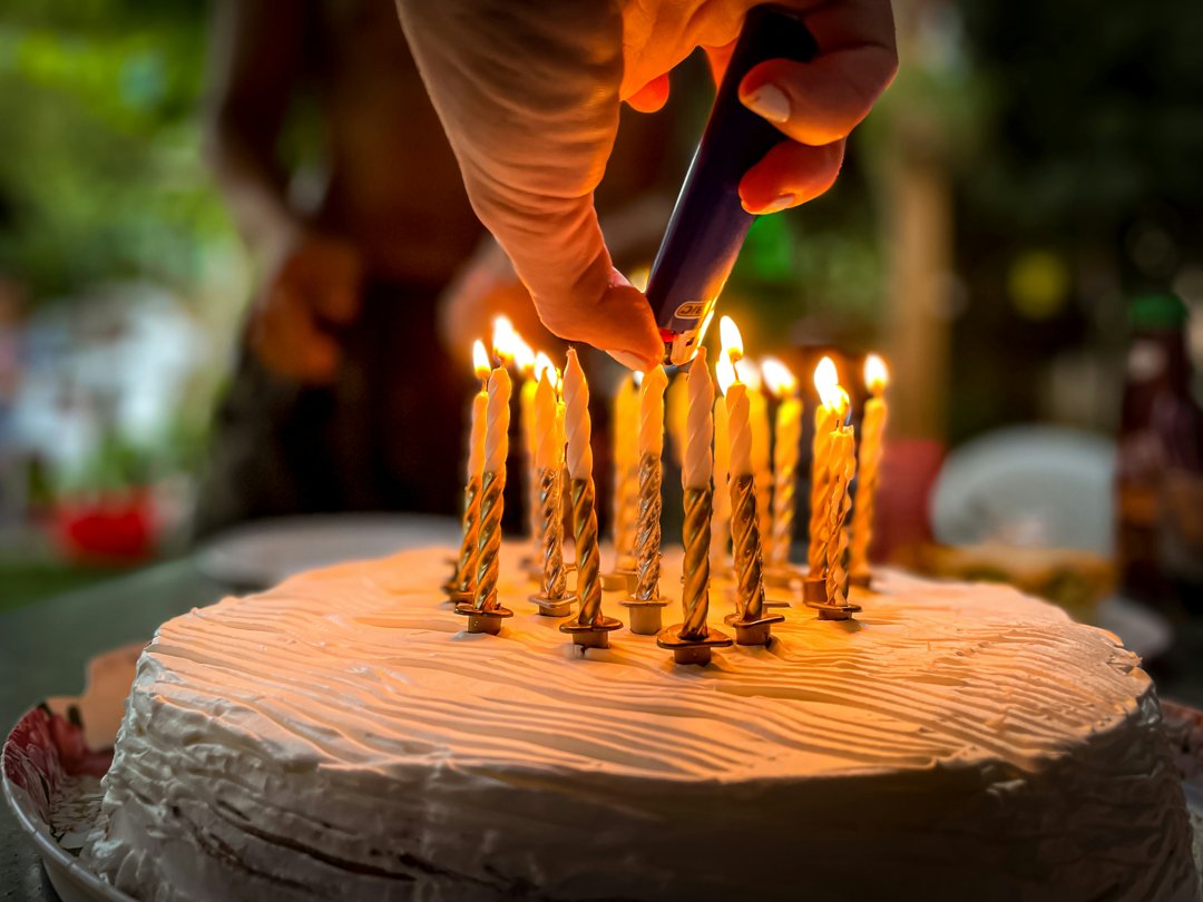 A woman's hand lighting candles on a cake | Source: Unsplash