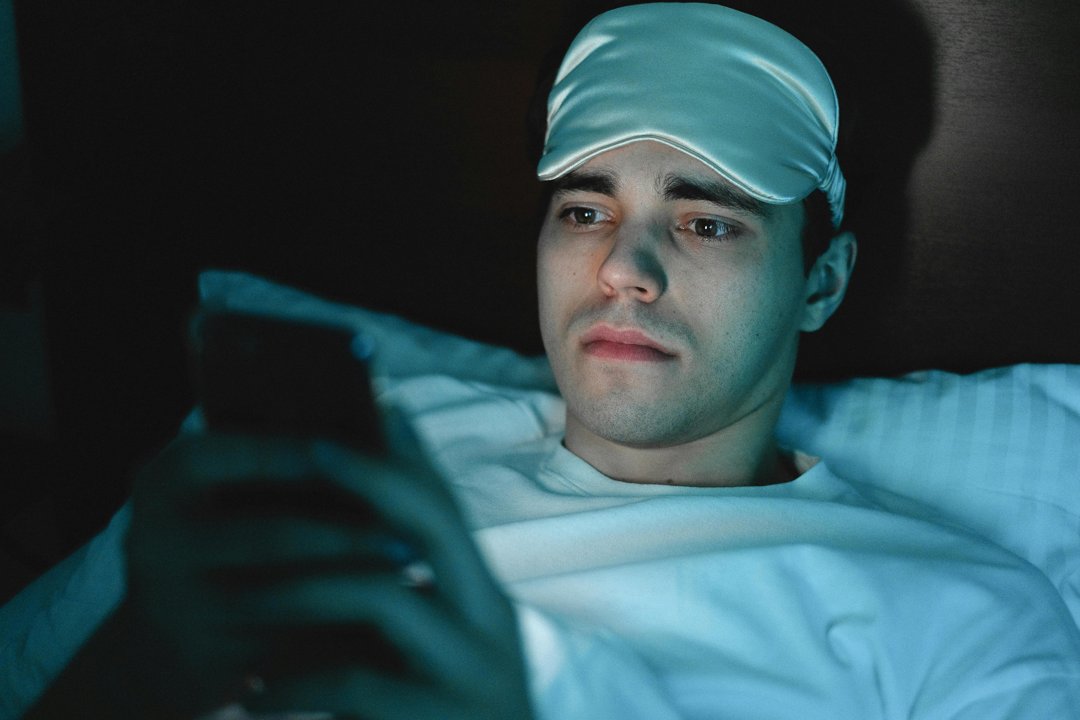 A serious man using his phone while in bed | Source: Pexels