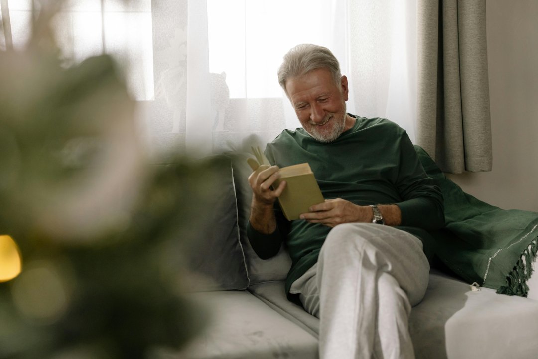 A smiling older man reading a book | Source: Pexels