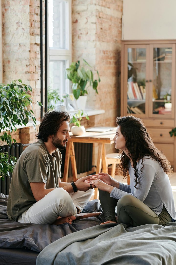 A couple sitting and talking on a bed | Source: Pexels