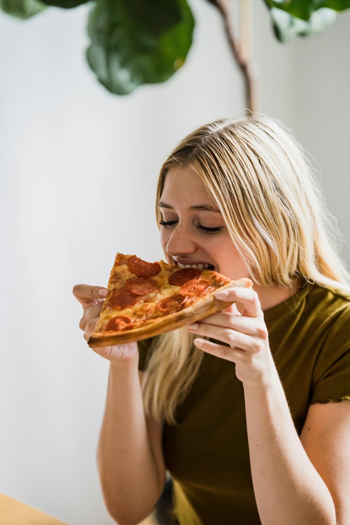 A happy woman eating pizza | Source: Pexels
