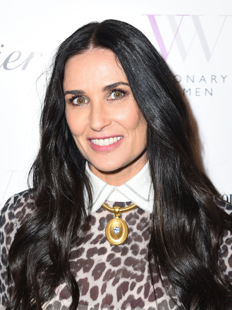 With a radiant smile and striking gaze, she stands poised in a chic leopard-print ensemble adorned with a bold gold pendant. Her long dark hair frames her face with classic grace, exuding modern sophistication. Demi Moore embodies confidence and timeless style in a moment that feels both vibrant and refined.
