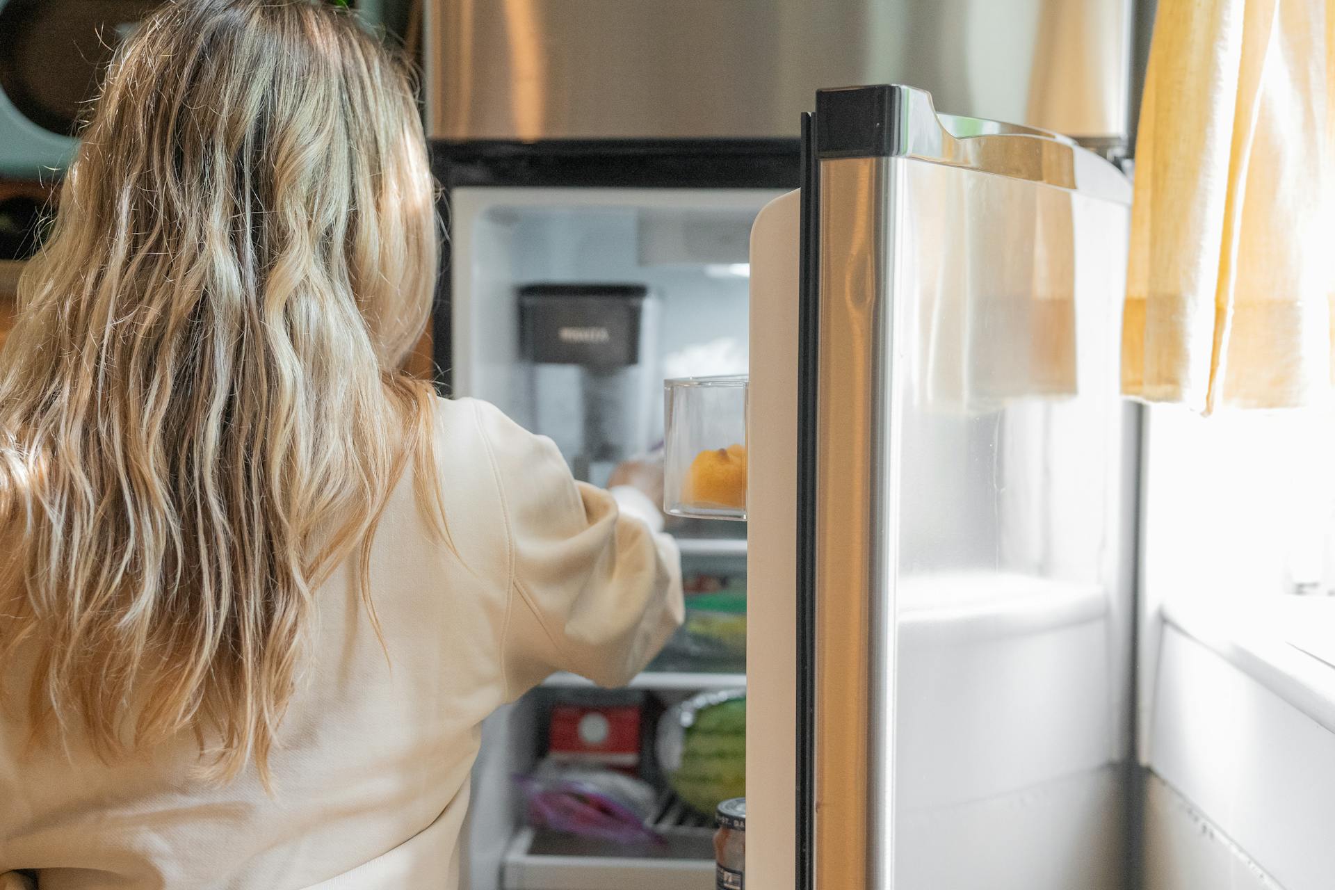Close-up shot of a woman getting some food from the refrigerator | Source: Pexels
