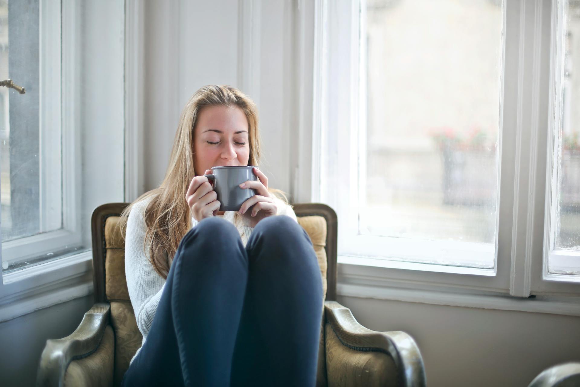Woman sitting on a sofa and having tea | Source: Pexels