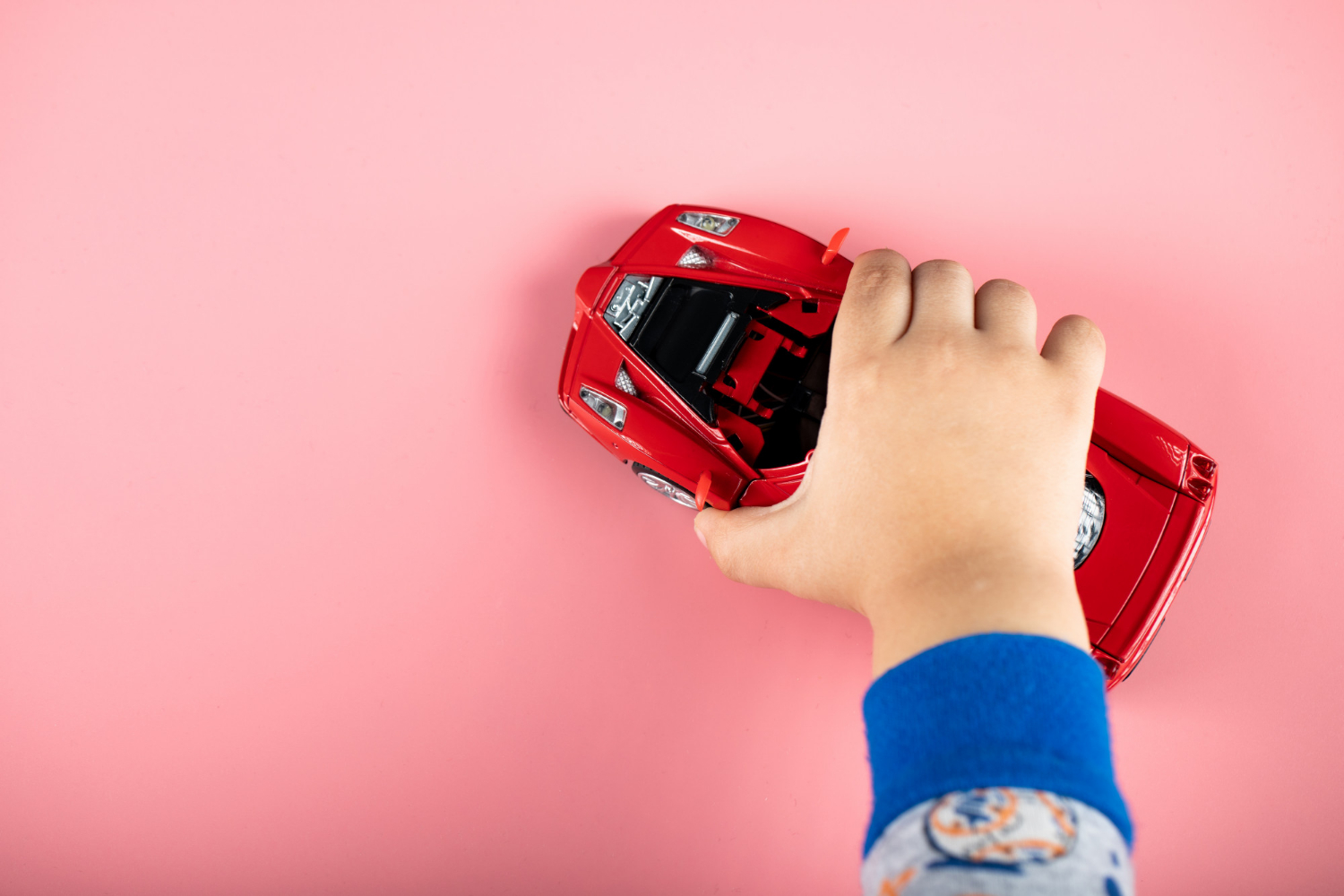 A child playing with a red toy car | Source: Freepik
