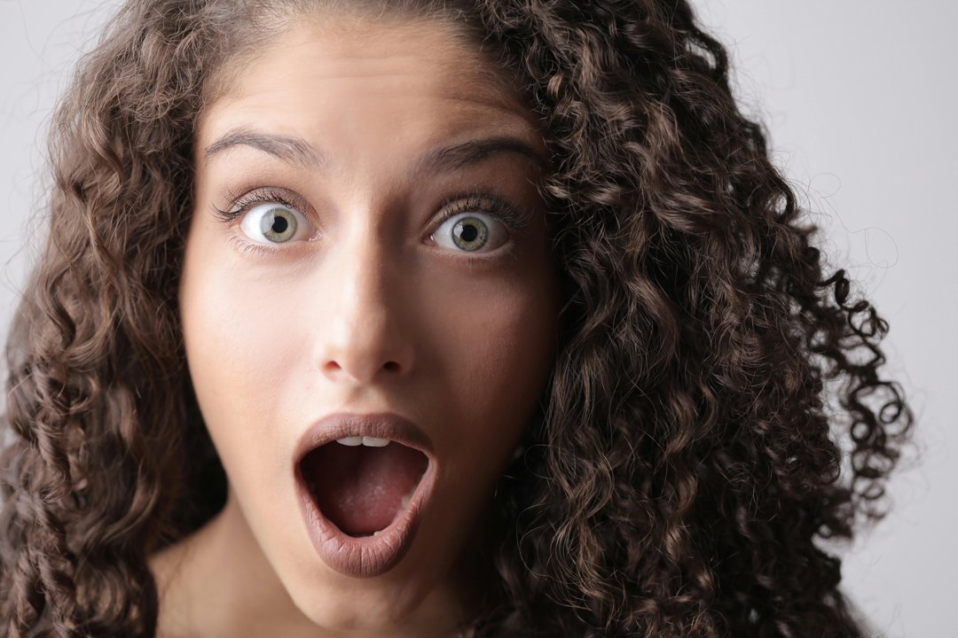 A shocked woman with brown curly hair | Source: Pexels