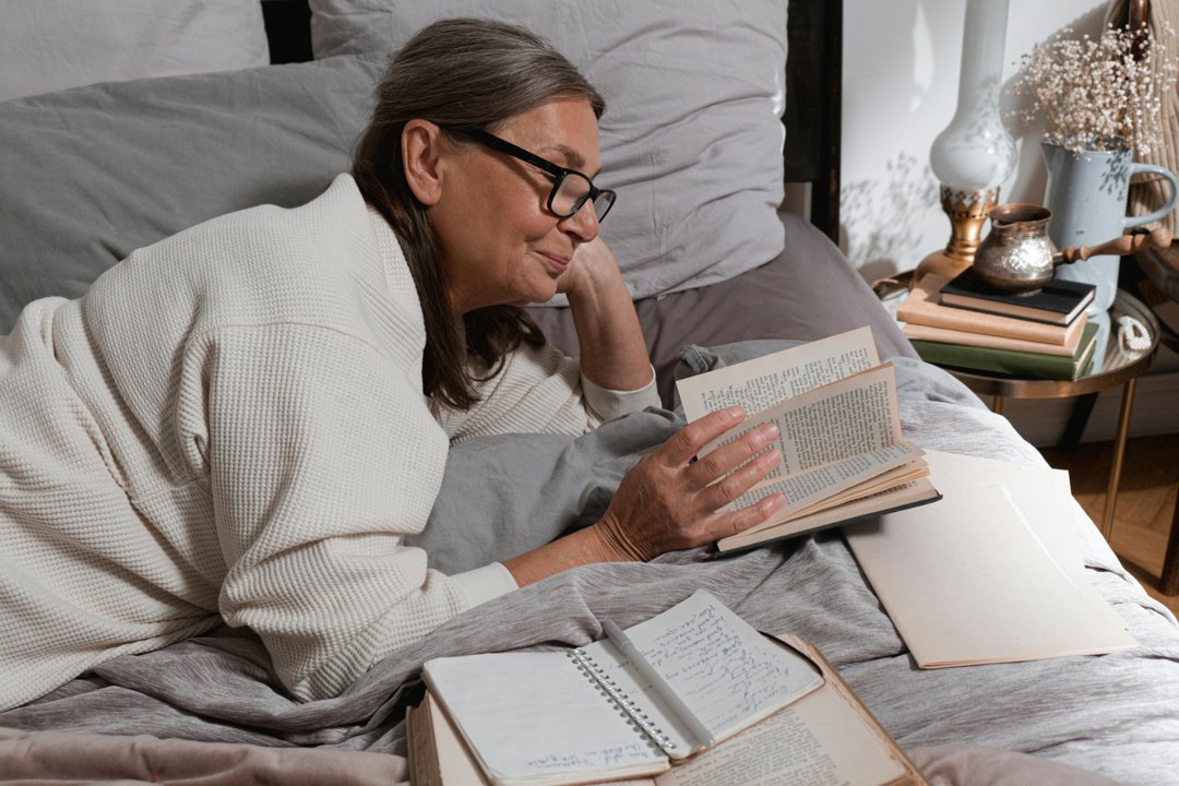 An older woman sitting on a couch and reading a book | Source: Pexels