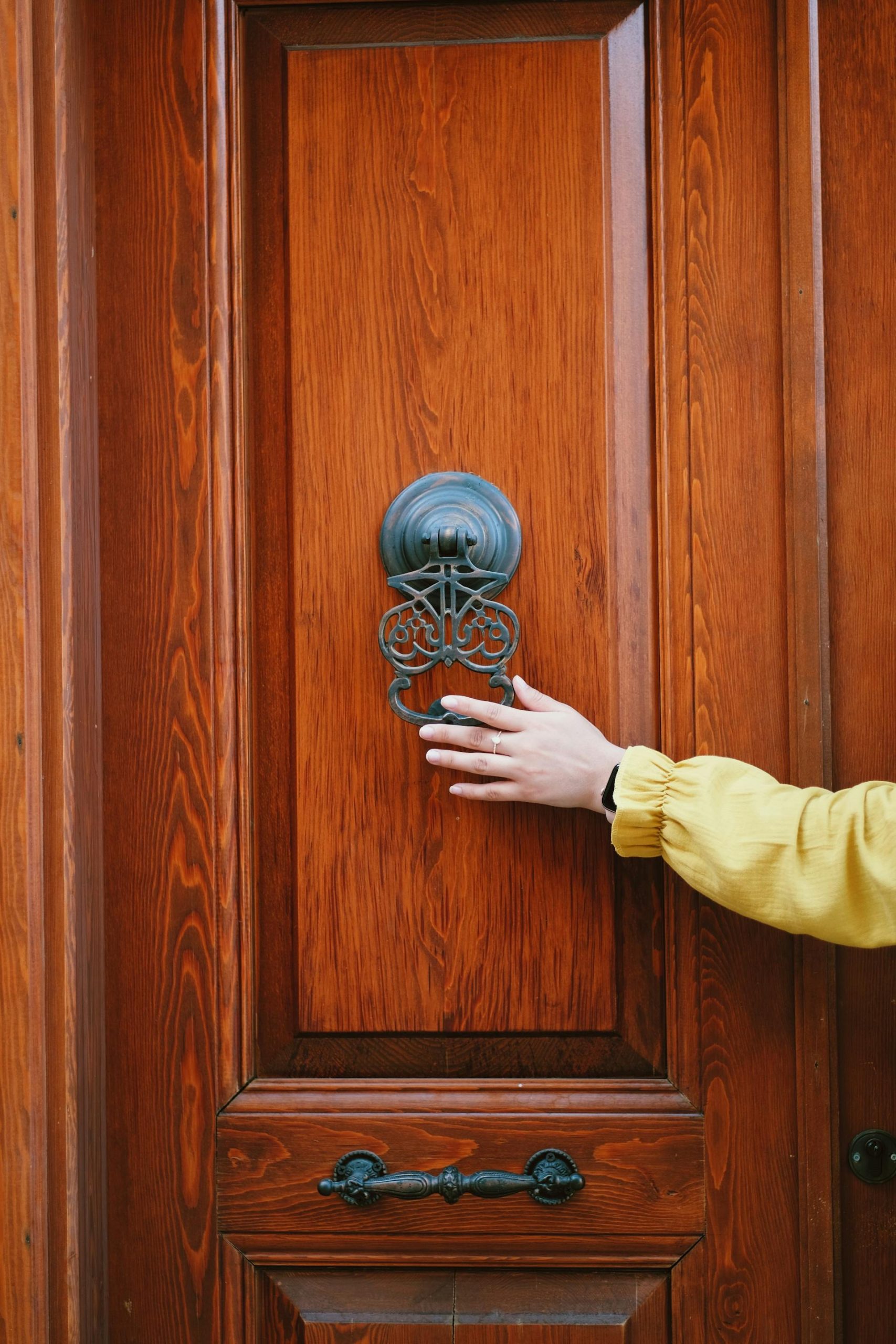 A distant shot of a person holding a door knocker | Source: Pexels