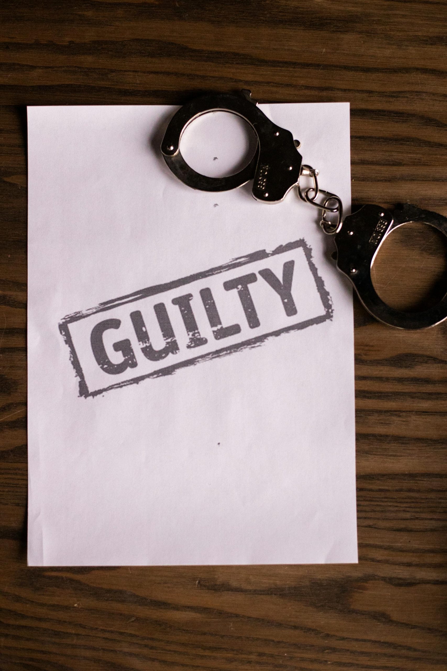A piece of paper and handcuffs lying on a wooden surface | Source: Pexels
