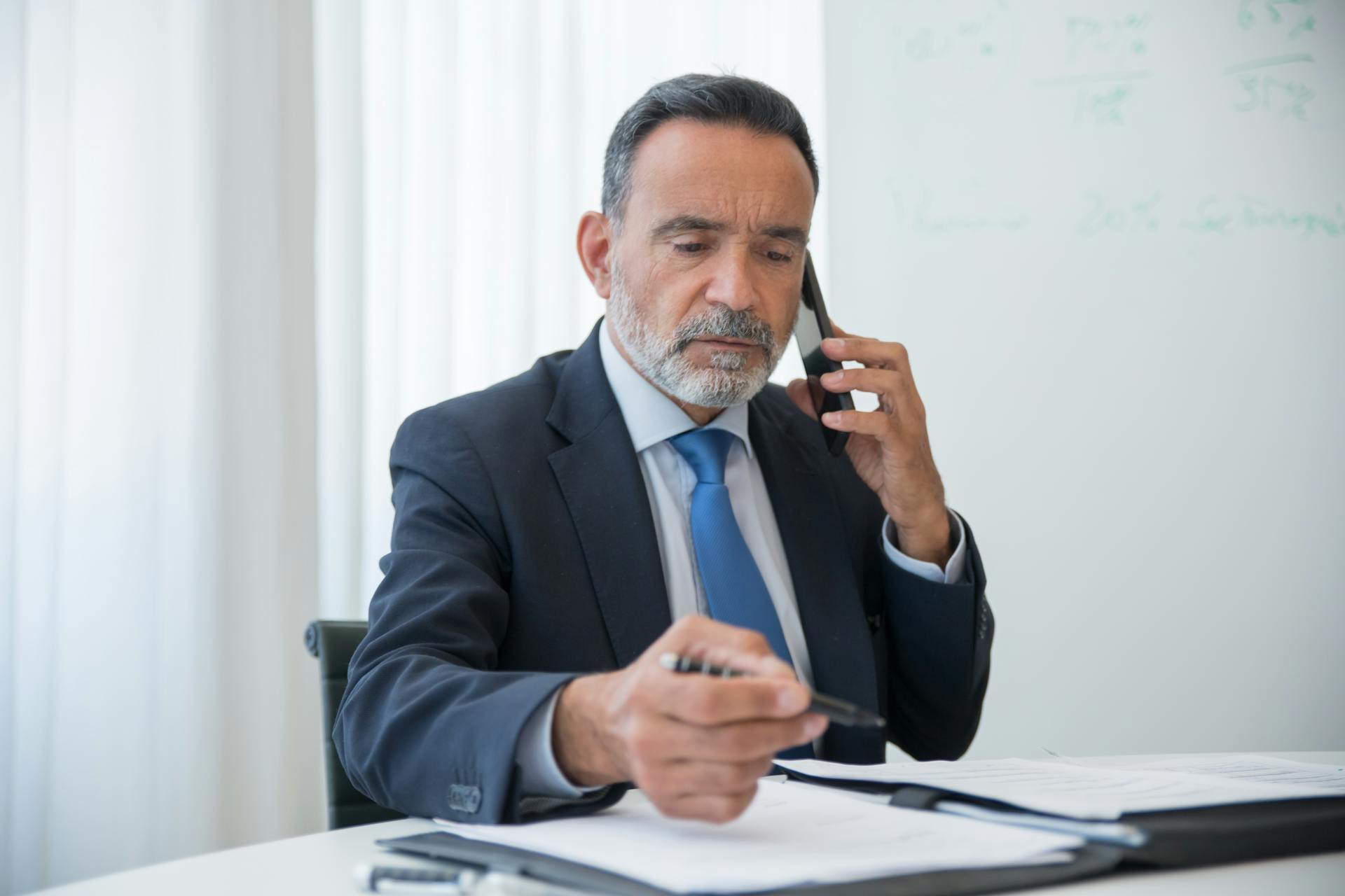 A man talking on his phone while looking at some documents | Source: Pexels