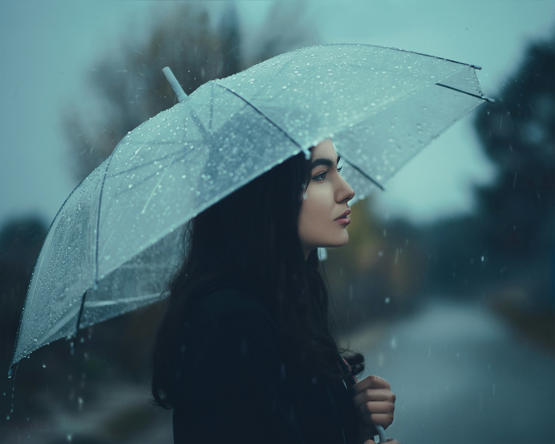 A woman standing in the rain with an umbrella | Source: Unsplash
