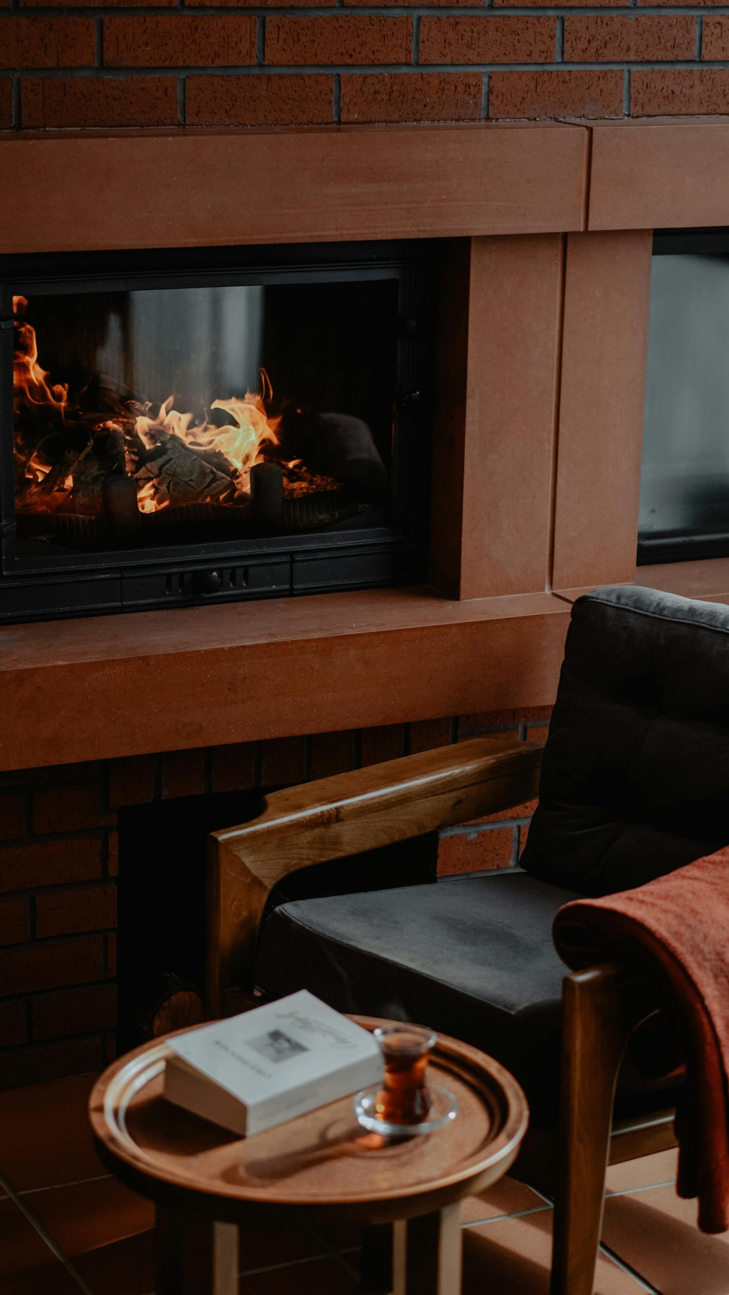 An armchair and a table lying next to an electric fireplace | Source: Pexels