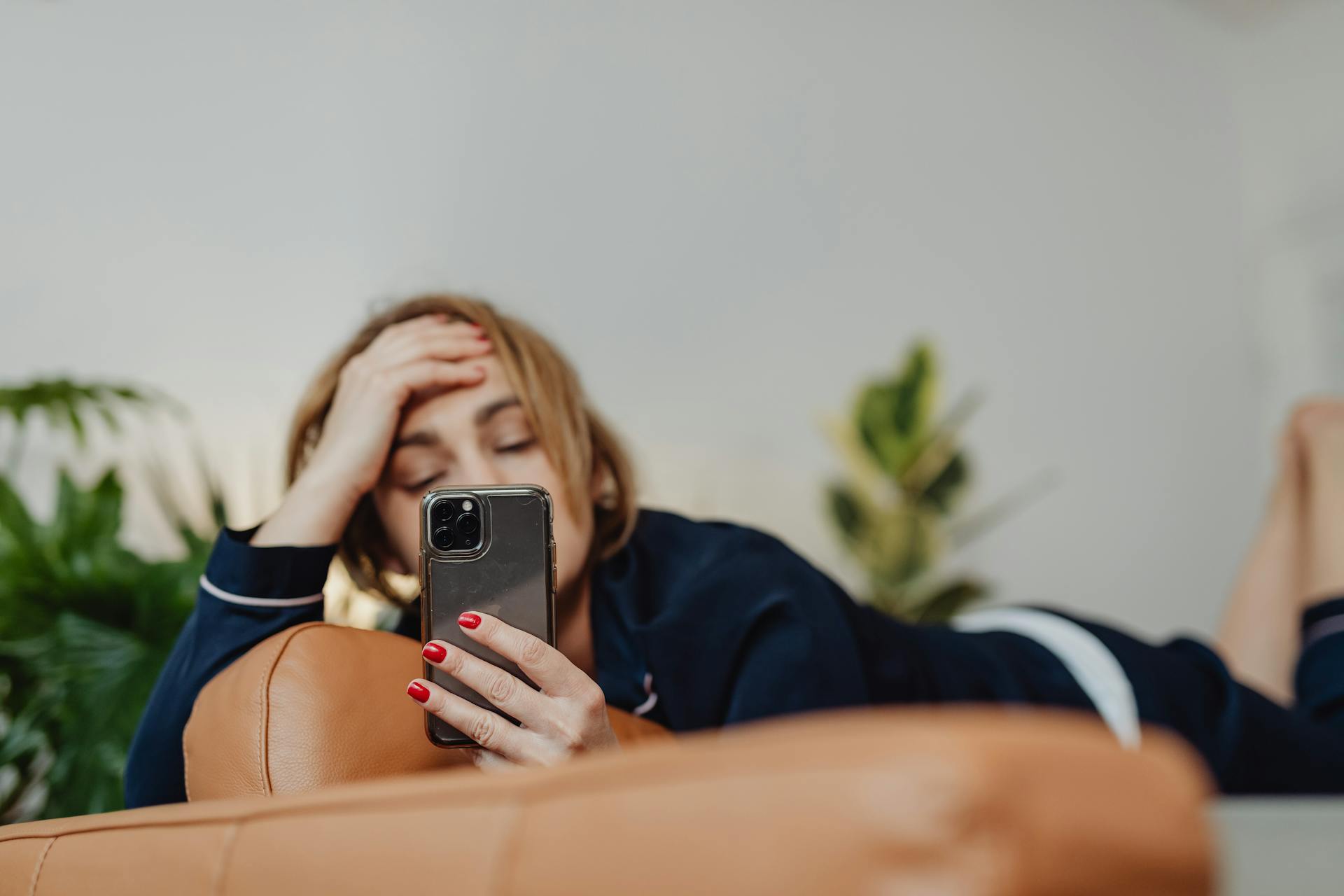 A woman lying down while looking at her phone | Source: Pexels