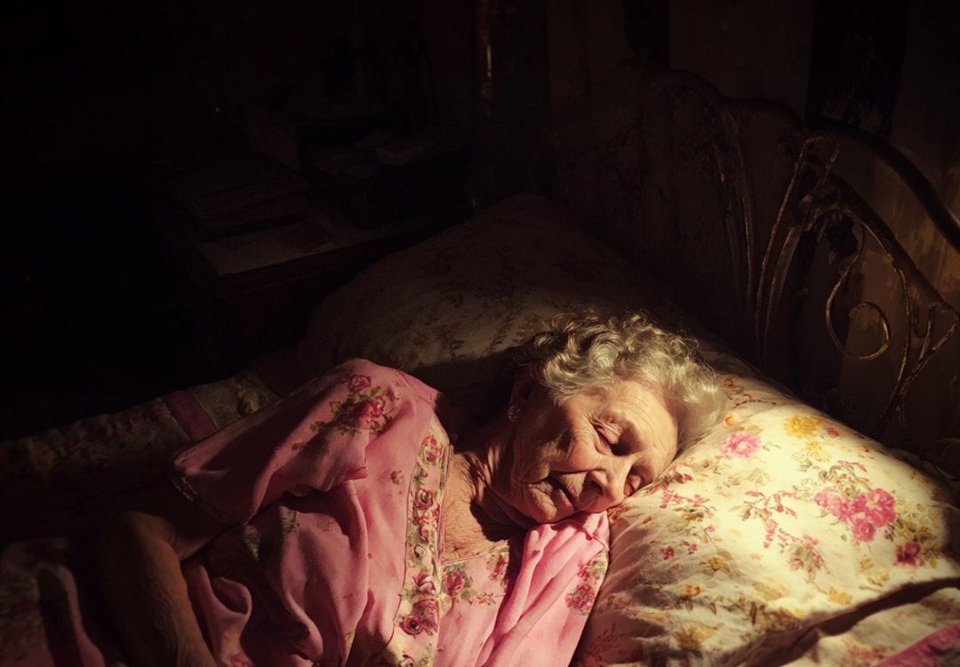 An old woman lying in her bed | Source: Midjourney