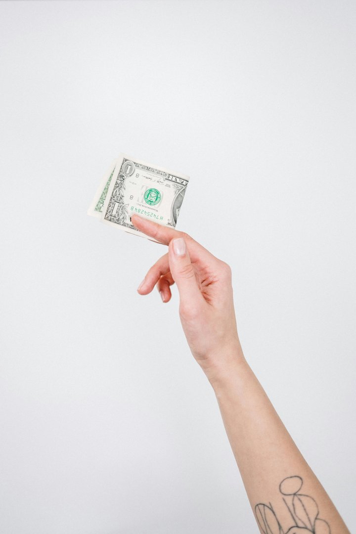A man holding out a folded dollar | Source: Pexels