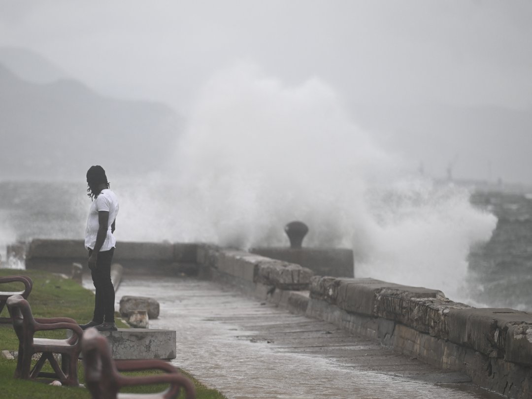 A man watches the waves crash into the walls as Hurricane Melissa hits. | Source: Getty Images