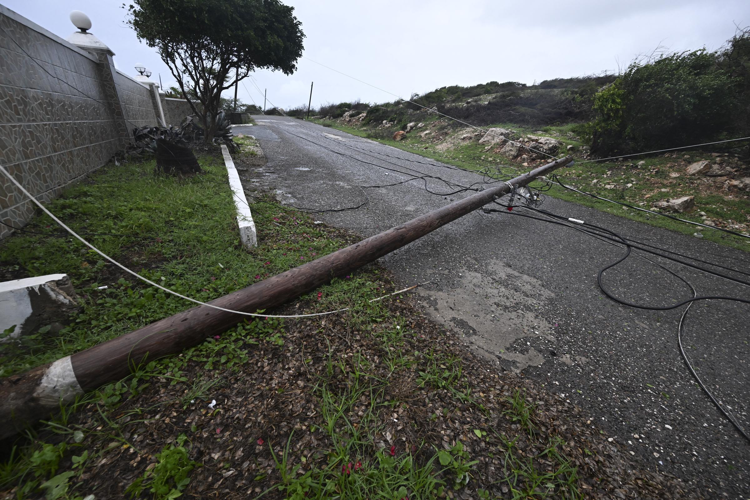 A fallen Jamaica Public Service light pole lies along Sugar Man's Beach Road in Hellshire, St. Catherine, as Jamaica begins to feel Hurricane Melissa's impact on October 26, 2025. | Source: Getty Images
