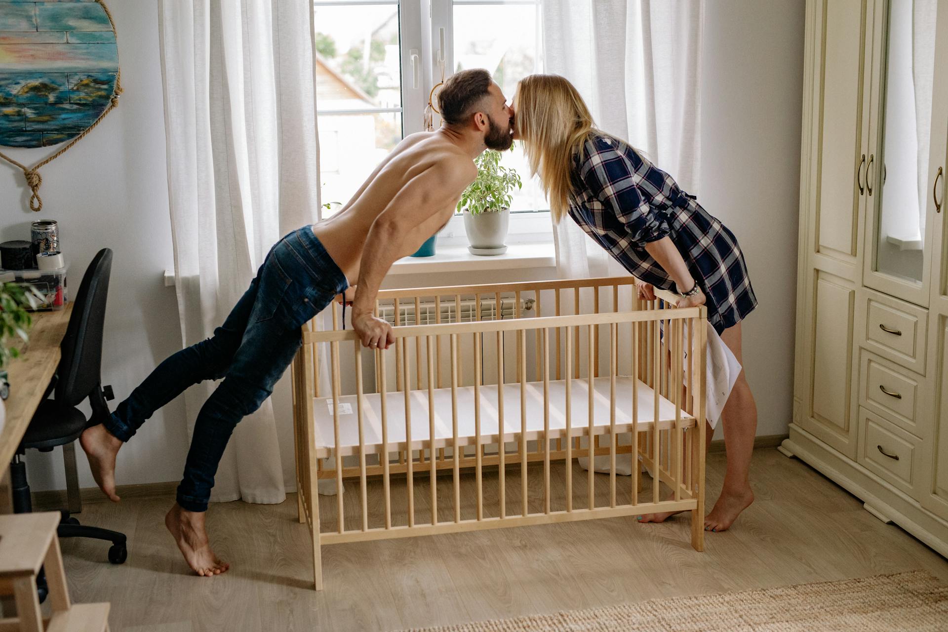 A couple kiss while setting up a baby crib | Source: Pexels