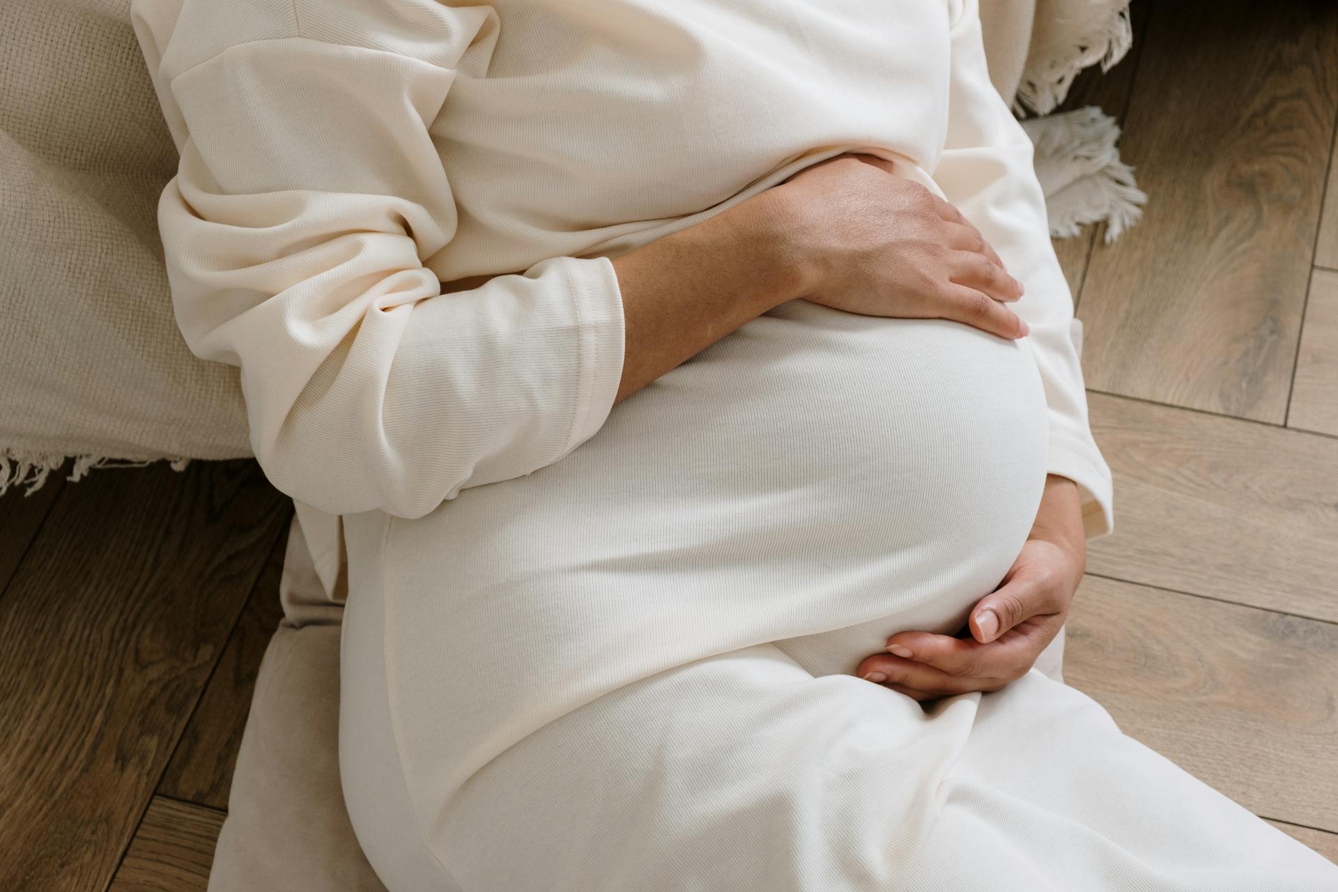 Close-up shot of a pregnant woman clutching her baby bump | Source: Pexels