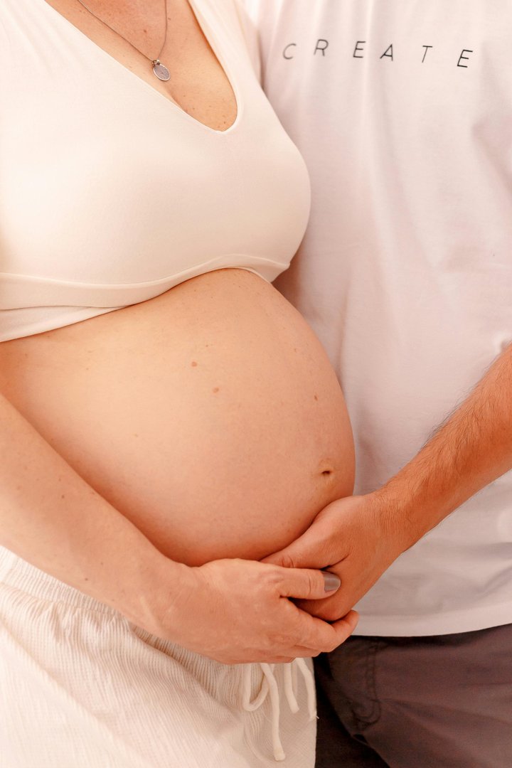 A woman placing a man's hand on her pregnant belly | Source: Pexels