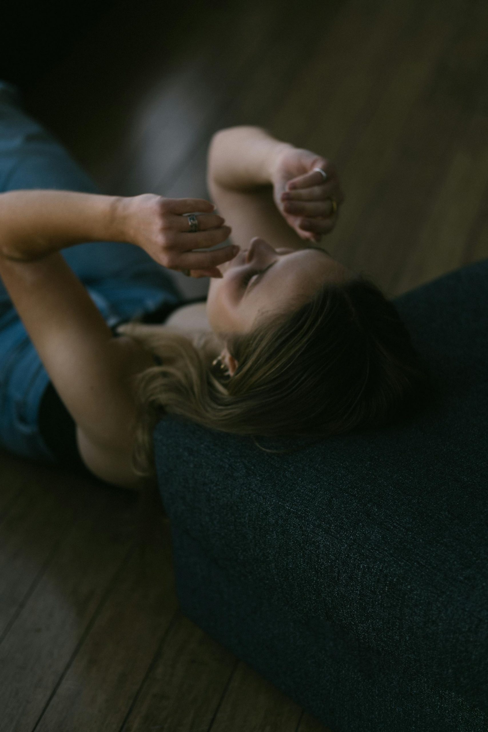A young woman lying down on the floor while resting her head against the sofa | Source: Pexels