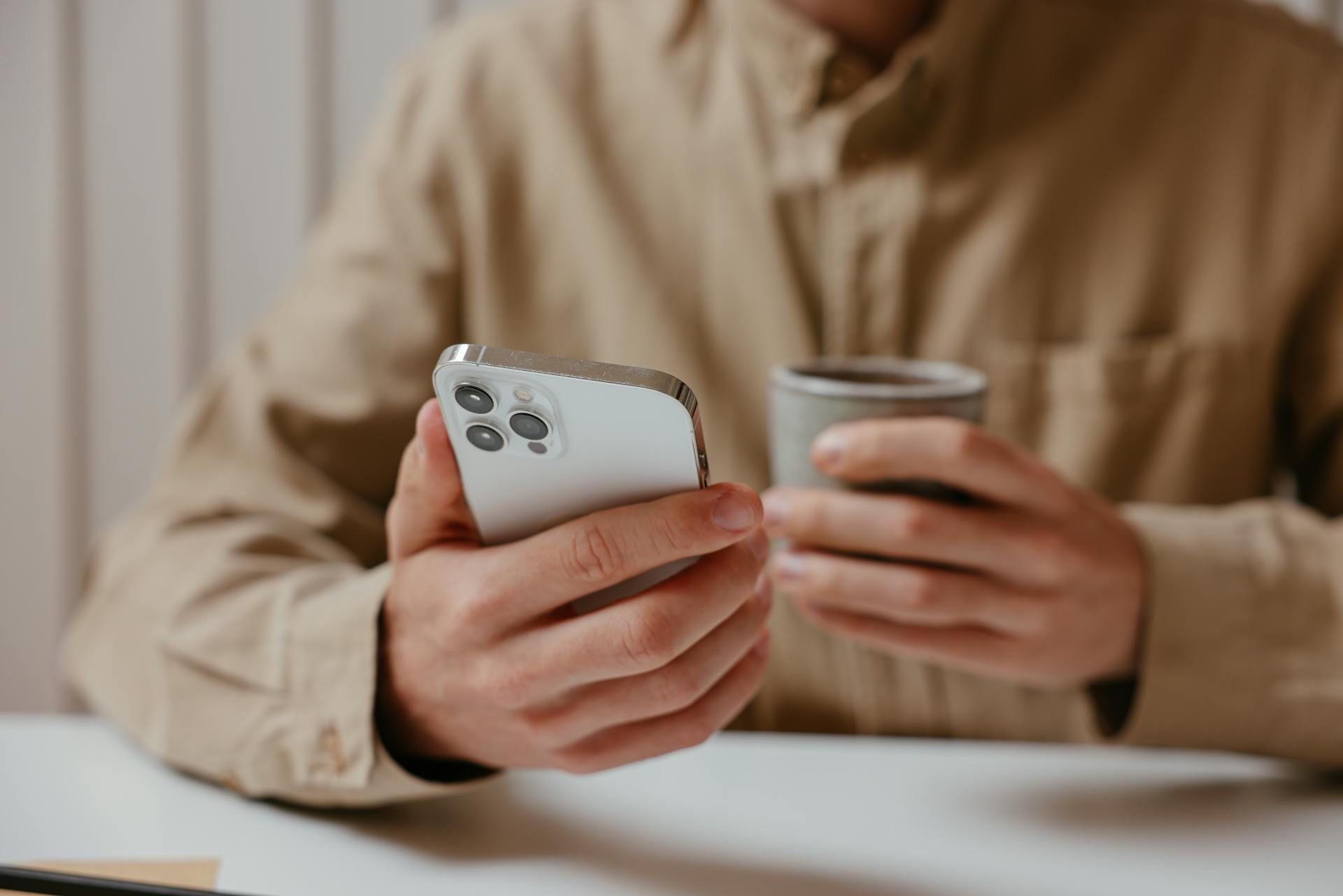 A man holding his phone and a cup | Source: Pexels