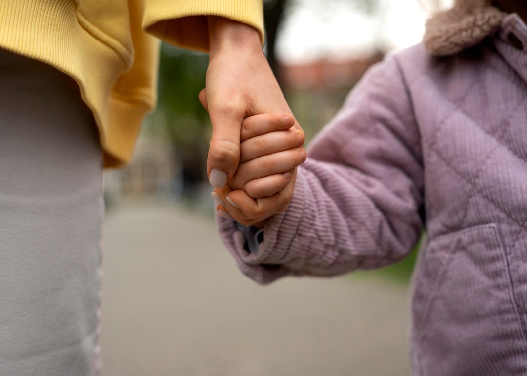 A woman holding a child's hand | Source: Freepik