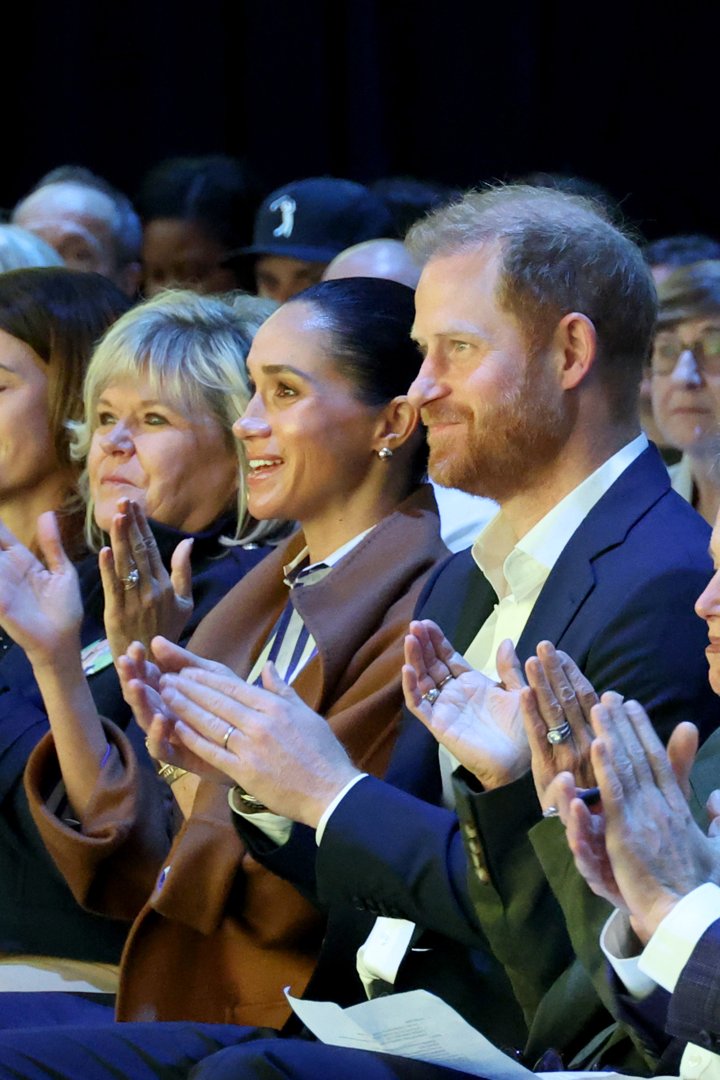 Meghan Markle and Prince Harry clapping while seated in the audience. | Source: Getty Images