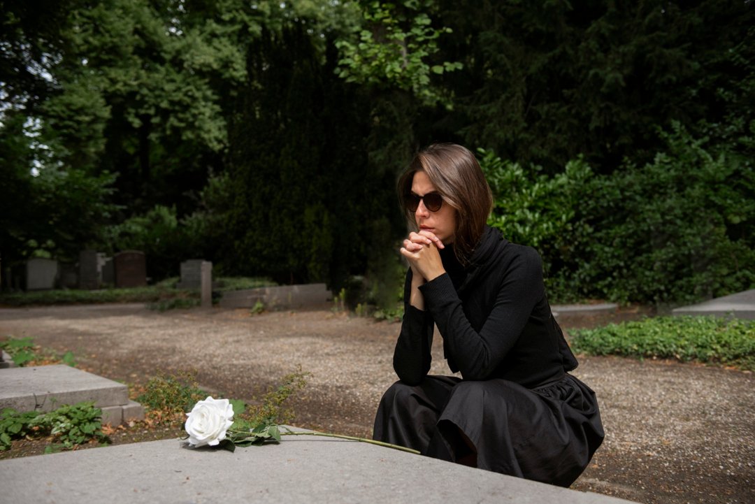 A woman sitting beside a grave | Source: Freepik