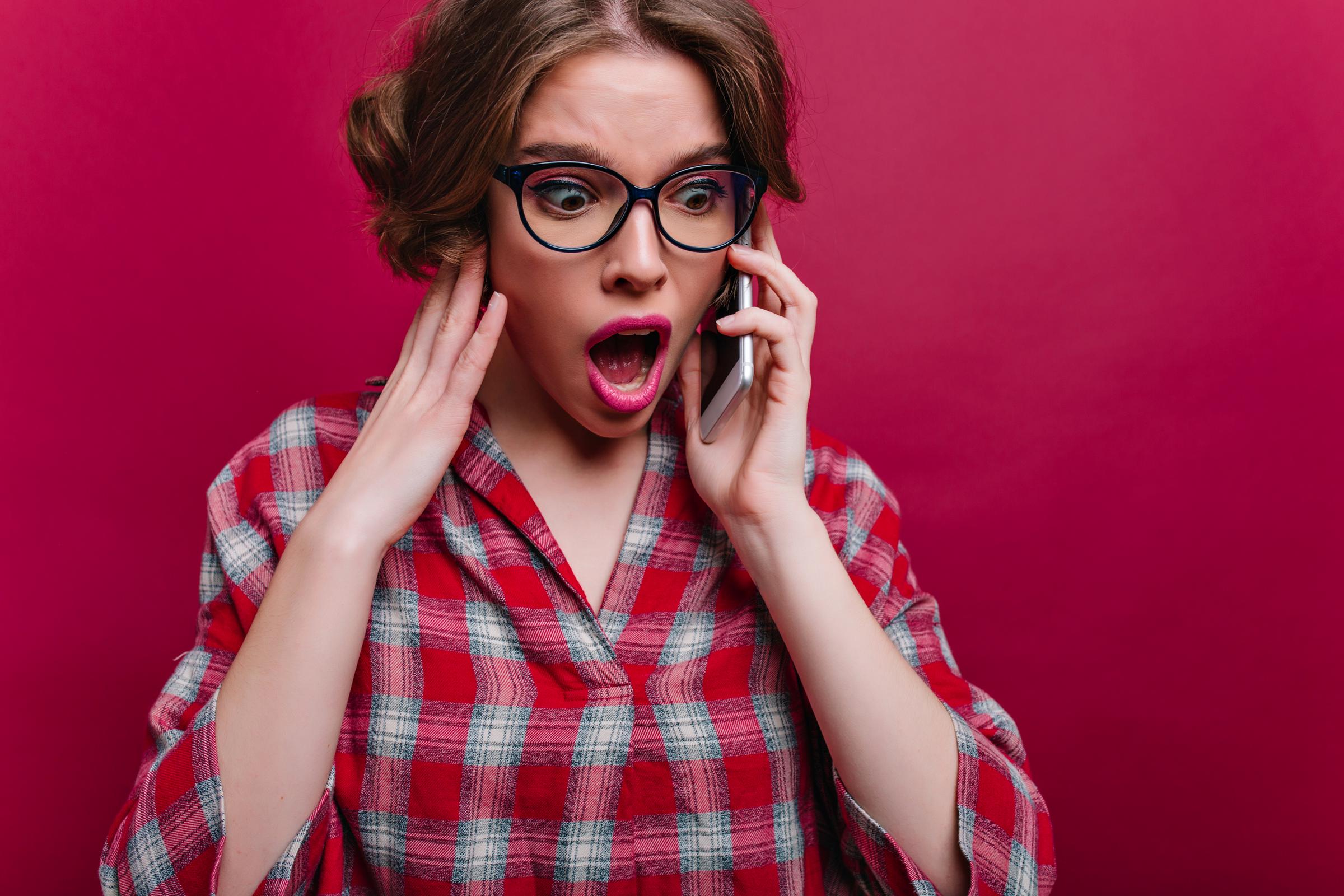 A shocked woman on a call | Source: Freepik