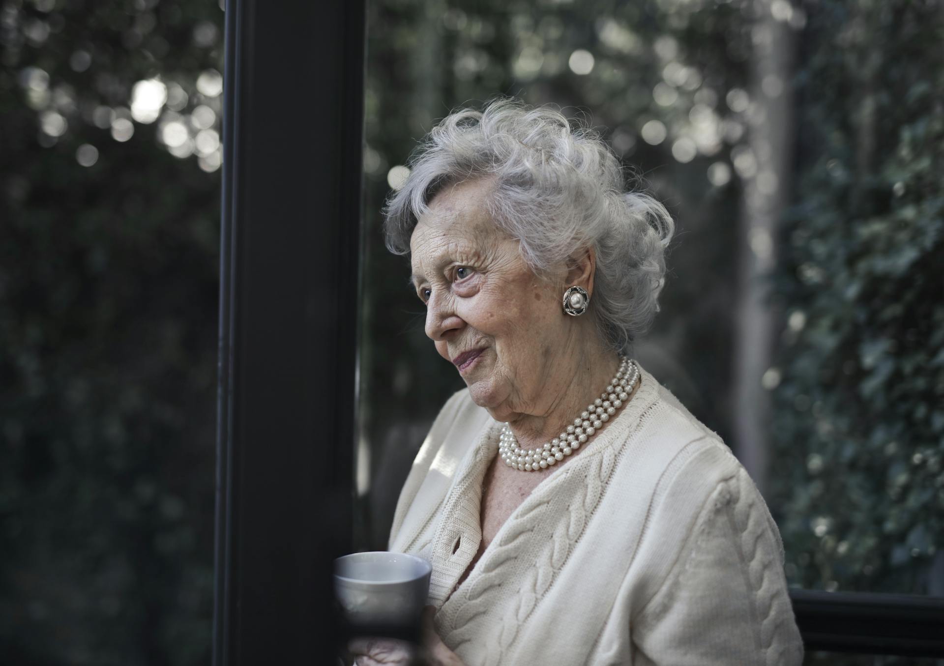 An older woman standing near a glass door | Source: Pexels