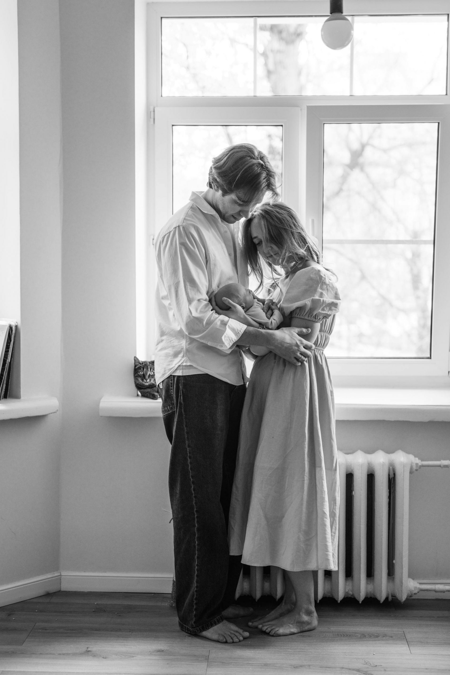 A couple holding their baby while standing by the window | Source: Pexels