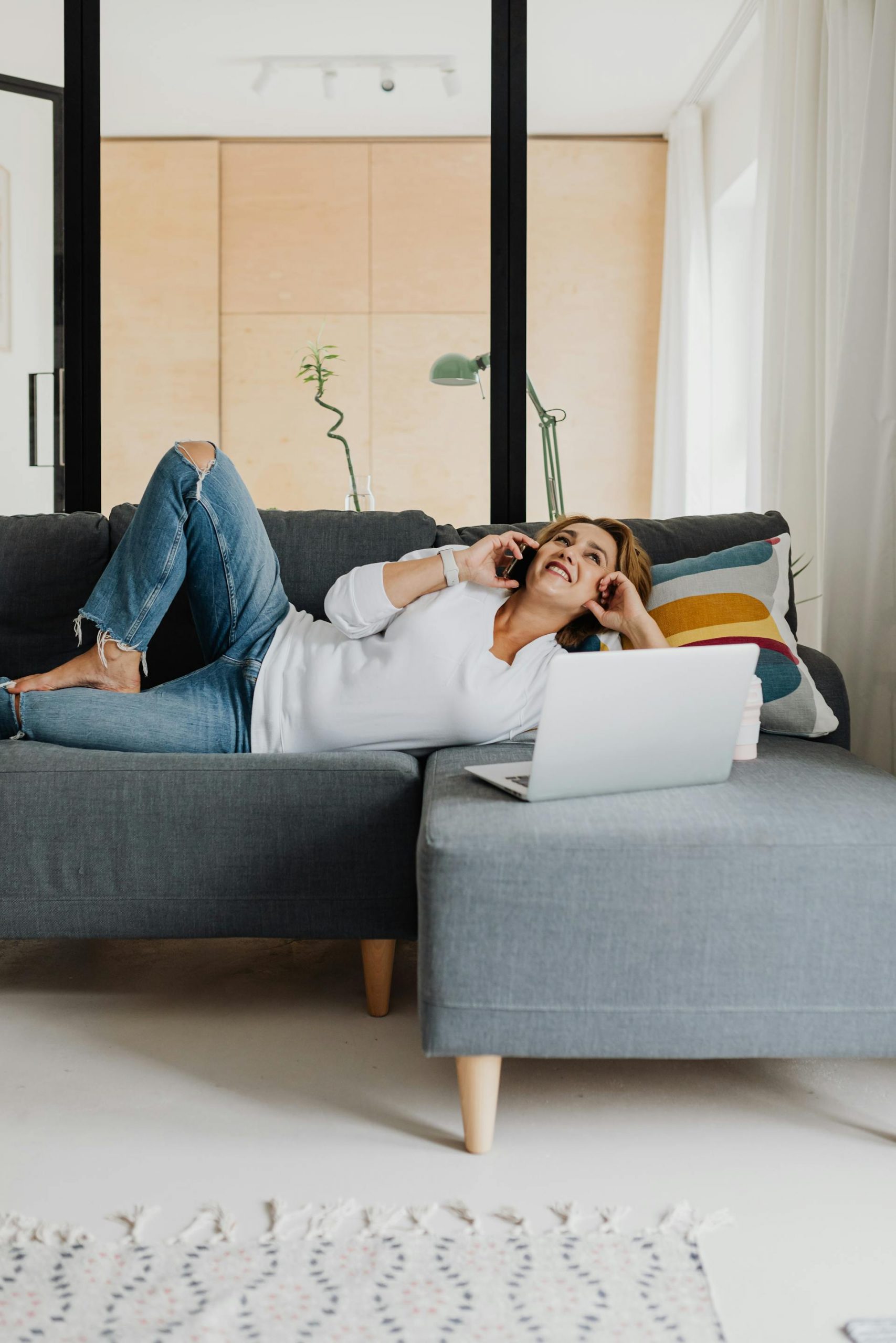 A woman lying on a couch and talking on the phone | Source: Pexels