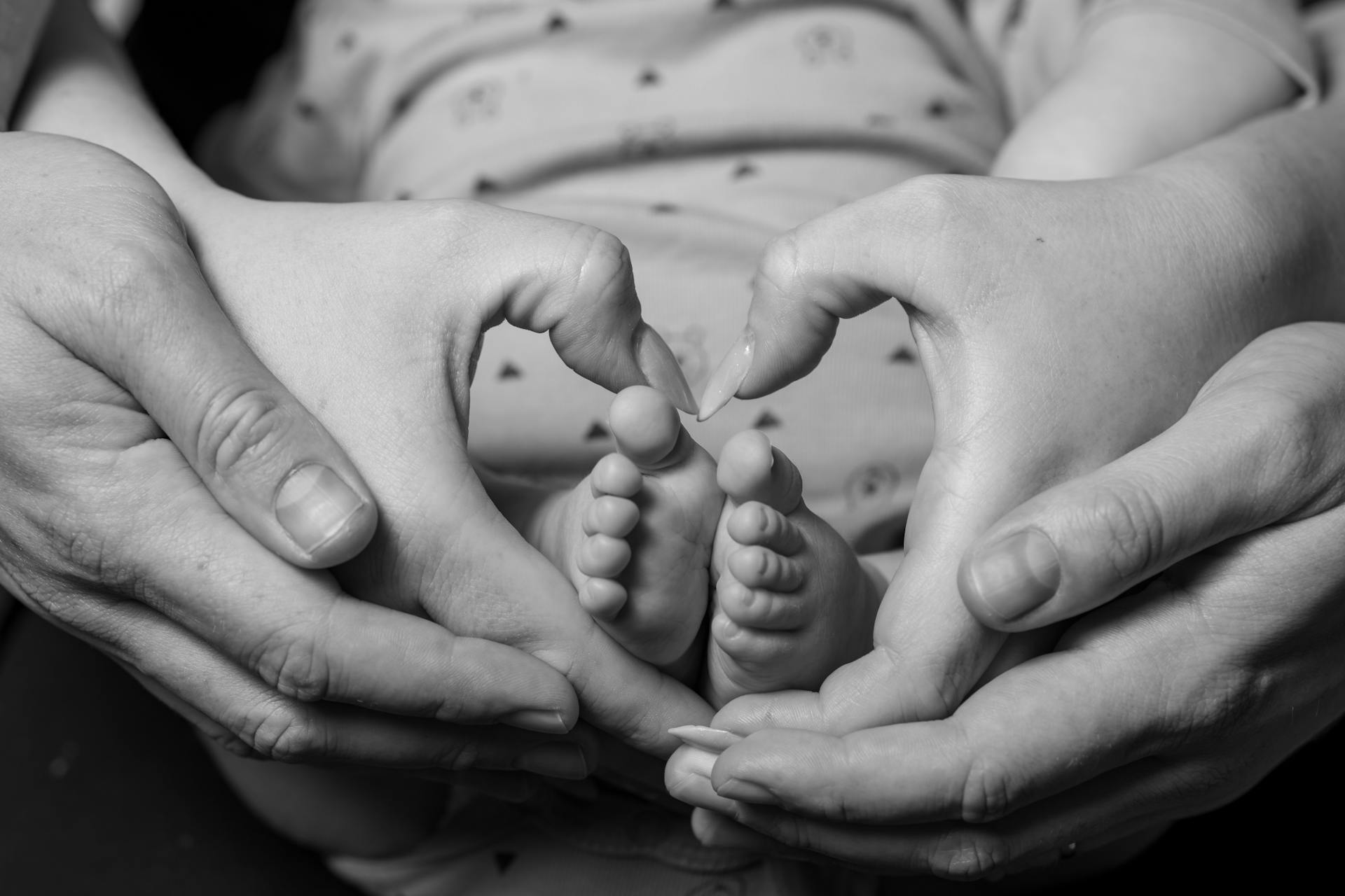 A couple forming a heart-shaped sign around their baby's feet | Source: Pexels