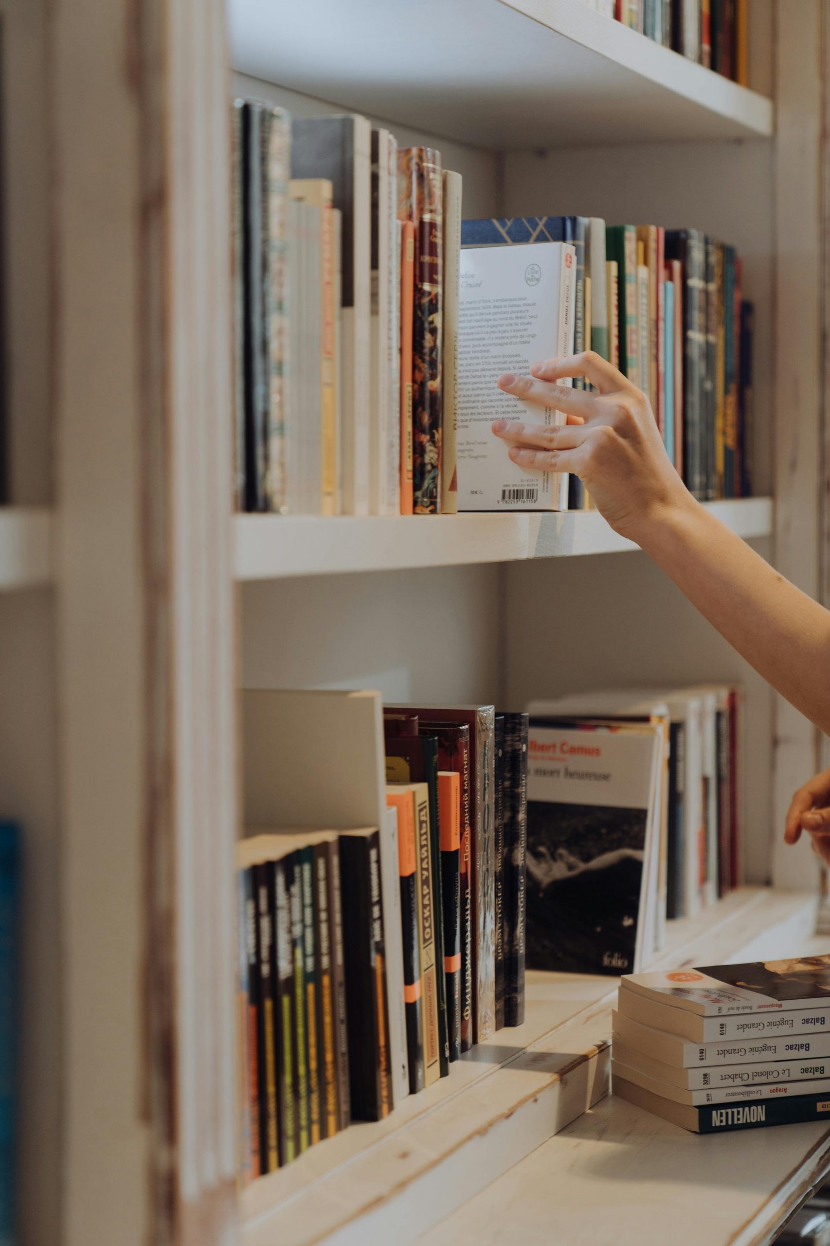 A person taking a book off a shelf | Source: Pexels