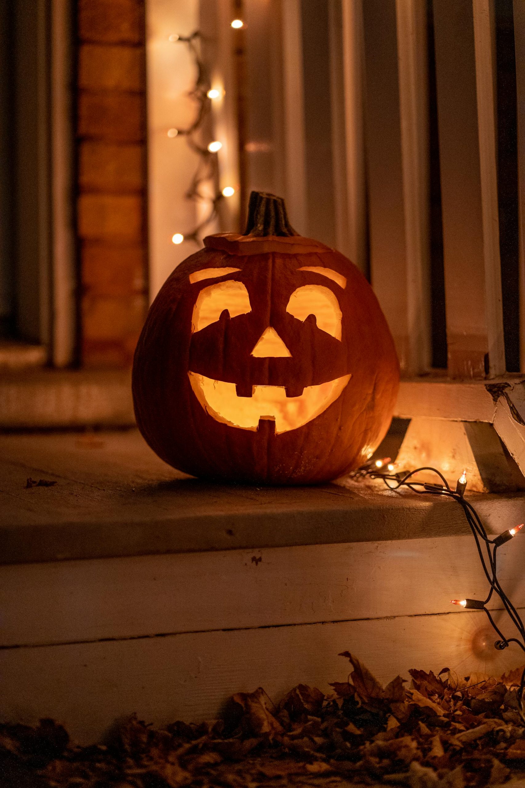 A carved pumpkin for Halloween lying next to twinkling lights | Source: Pexels